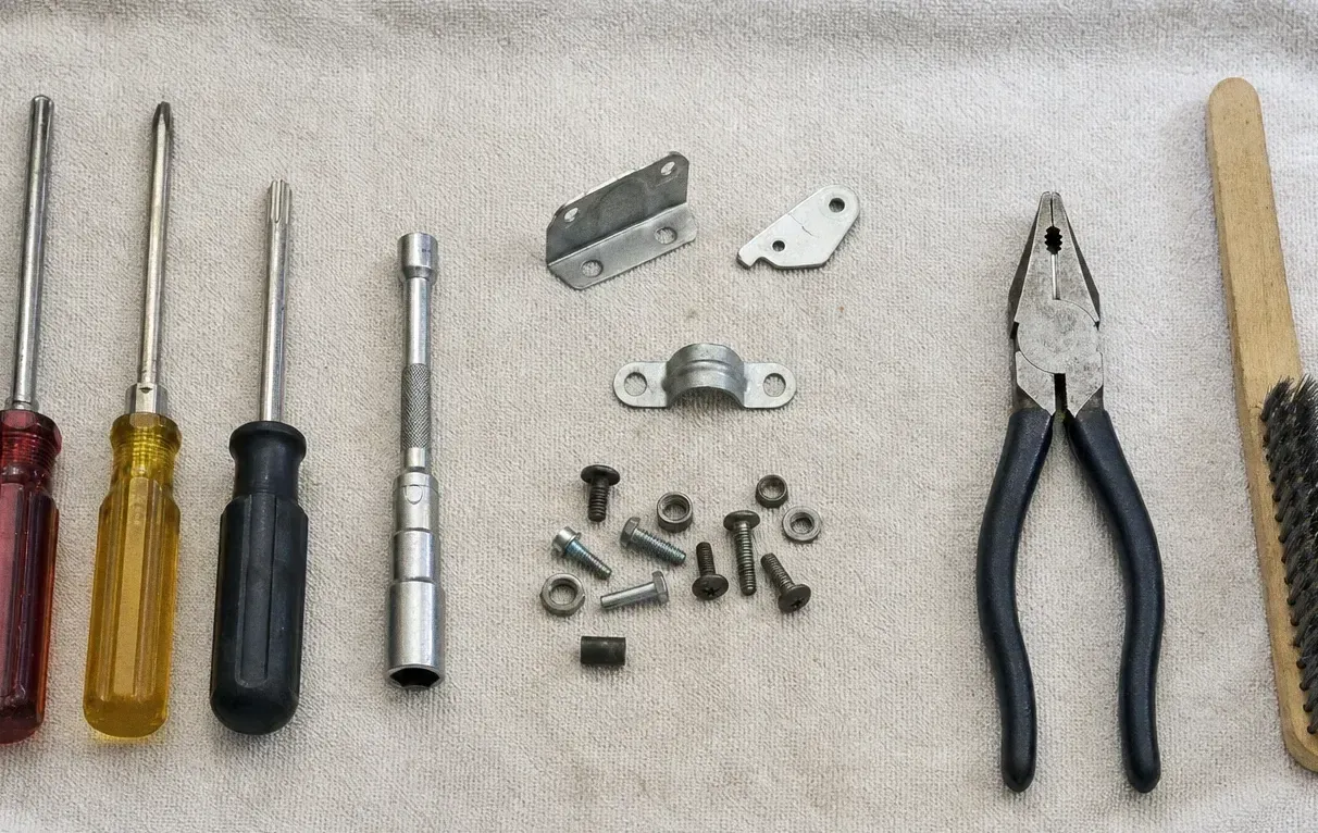 Two steel mounting plates, a socket and nut driver, bolts and washers arranged on a canvas cloth with pliers
