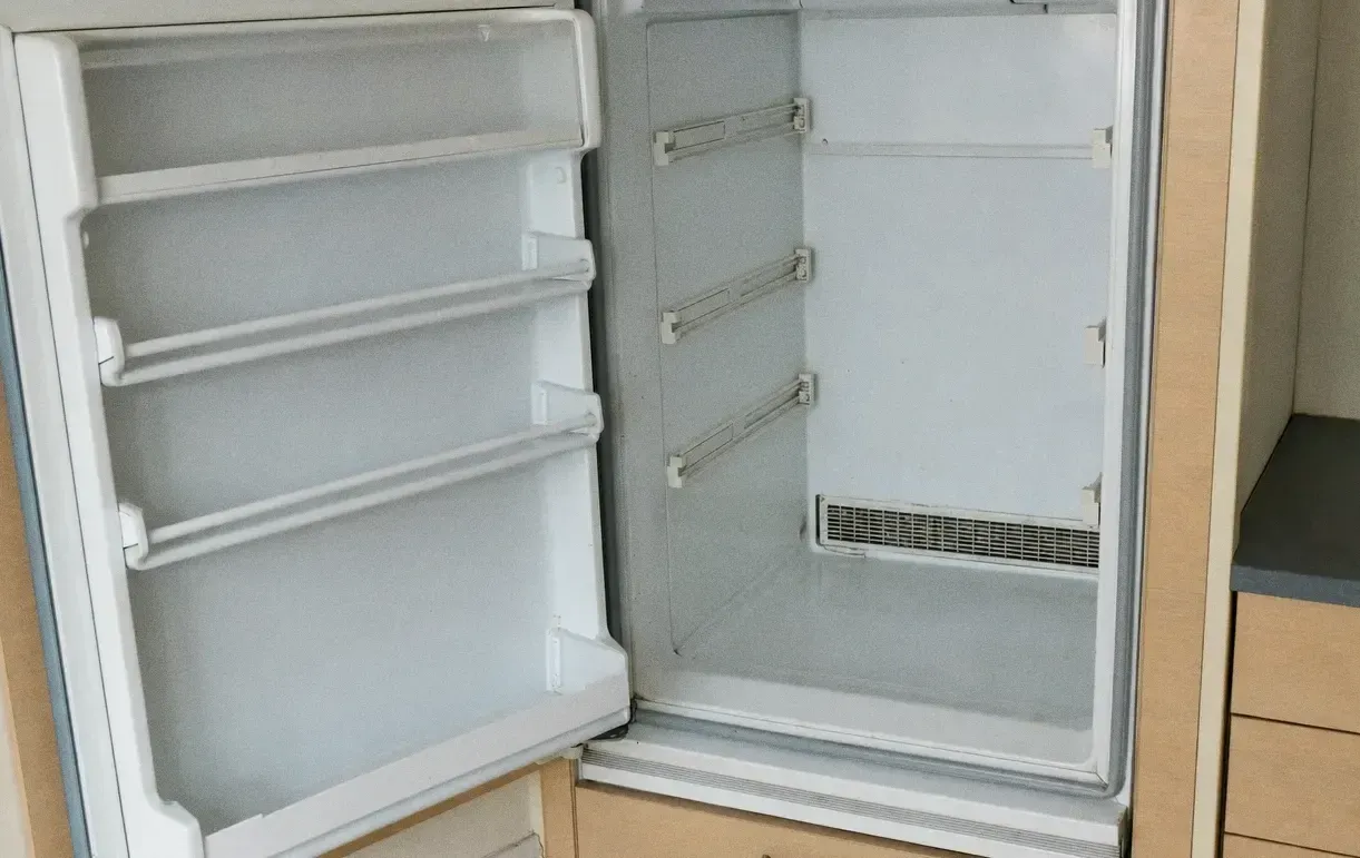 A refrigerator standing open, white moulded door bins on the door and an air grille on the interior back wall